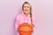 Beautiful young blonde woman holding basketball ball smiling and laughing hard out loud because funny crazy joke