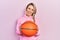 Beautiful young blonde woman holding basketball ball sticking tongue out happy with funny expression