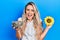 Beautiful young blonde woman holding sunflower seeds an flower celebrating crazy and amazed for success with open eyes screaming