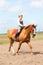 Beautiful young blonde woman riding chestnut horse