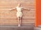 Beautiful young blonde woman standing hands spread on the background wall of wooden planks. Toned in warm colors