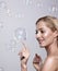 Beautiful young blonde woman touches the bubble with her finger