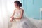 Beautiful young bride with dark curly hair in luxurious wedding dress posing at room