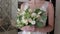 Beautiful young bride holding bridal bouquet of pastel roses, in a hotel.