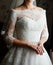 Beautiful young bride in white dress waiting for the groom indoors. Elegant charming young brunette bride posing indoors.