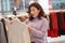 Beautiful young brunette female refreshing her wardrobe, attractive astonished woman searching for new clothing in shopping mal,