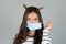Beautiful young brunette with a medical protective mask on a gray background.