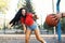 A beautiful young brunette is playing basketball with her boyfriend and is trying to pick up the ball