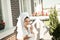 Beautiful young brunette woman wearing dressing gown and white towel on her head enjoying cup of coffee on the terrace