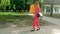 Beautiful young business girl in red suit and sunglasses walks down the street on high heels