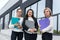 Beautiful and young business women with documents and folders posing outside office building