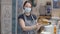 Beautiful young Caucasian cook or waitress in Covid-19 face mask posing in restaurant with food. Positive slim woman