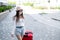 A beautiful young Caucasian woman in a medical mask walks down the street with a red suitcase. A girl with luggage