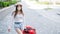 A beautiful young Caucasian woman in a medical mask walks down the street with a red suitcase. A girl with luggage