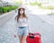 A beautiful young Caucasian woman in a medical mask walks down the street with a red suitcase. A girl with luggage