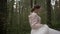 A beautiful young cheerful and joyful bride in a wedding dress and a delicate sweater runs and spins in the forest. Slow