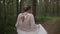 A beautiful young cheerful and joyful bride in a wedding dress and a delicate sweater runs and spins in the forest. Slow