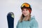 A beautiful young chew in an extreme sports suit, a hat and a helmet with a mask on the winter slope is holding alpine