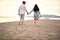 Beautiful young couple in casual barefoot walk on sandy beach, holding hands