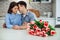 Beautiful young couple is celebrating at home. Handsome man is giving his girlfriend a bouquet of pink tulips