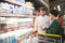 A beautiful young couple chooses dairy products in a supermarket. The girl reads the milk ethics in the store