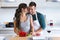 Beautiful young couple having romantic moments, hugging and kissing while cutting vegetables in the kitchen at home.