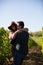 Beautiful young couple having a sweet moment between rows of vineyard