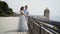 Beautiful young couple on honeymoon. Action. Newlyweds on stone observation deck admiring seascape. Beautiful newlyweds