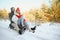 Beautiful young couple in love having fun on a winter vacation in mountains, boyfriend pushing girlfriend on a sled, enjoying