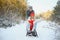Beautiful young couple in love having fun on a winter vacation in mountains, boyfriend pushing girlfriend on a sled, enjoying