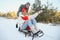 Beautiful young couple in love having fun on a winter vacation in mountains, boyfriend pushing girlfriend on a sled, enjoying