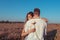 Beautiful and young couple man and woman, in summer wheat field, behind gift is flower, surprise and tenderness, happy