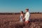 Beautiful young couple, man and woman, walking wheat field in summer, holding each other`s hand, smiling happy. Romantic