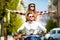 Beautiful young couple riding scooter together while happy woman raising arms and smiling