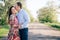 Beautiful young couple sensual hugging and kissing on road in sunshine among spring field and trees. Happy family in love