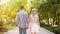 Beautiful young couple strolling through sunlit bright green park, romantic date