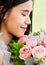 A beautiful young cute black long hair Asian woman holding a sweet color roses bouquet and closed eyes with happy and deep love