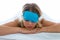 Beautiful young exhausted woman with sleep mask suffering insomnia trying to sleep over white background.