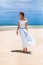 Beautiful young fashionable woman in white dress at the beach