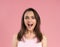 Beautiful young female emotional smiling and surprised looking at camera. Young woman with dark hair in pink t-shirt