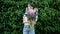 Beautiful young female florist holding bouquet on wall background and offers to buy it for you