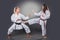 Beautiful young female karate player doing kick on the gray background