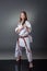 Beautiful young female karate player posing on the gray background