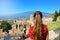 Beautiful young female model in the ruins of the ancient Greek theater in Taormina with the Etna volcano on the background, Sicily