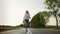 Beautiful young female with nice hat smiling and running on asphalt road while travelling through Europe countryside