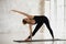 Beautiful young female performs Extended Triangle Pose or Utthita Trikonasana