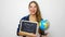 Beautiful young female student holding globe and blackboard with written back to school