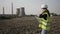 Beautiful young female technician specialist examining power plant area and taking note on clipboard -