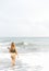 Beautiful young Filipina woman,playfully paddling in the shallow waves of the long sandy beach at Iba,Zambales,Luzon,Philippines