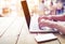 beautiful young freelance woman`s hands busy working on her laptop sitting at wooden table in a coffee shop